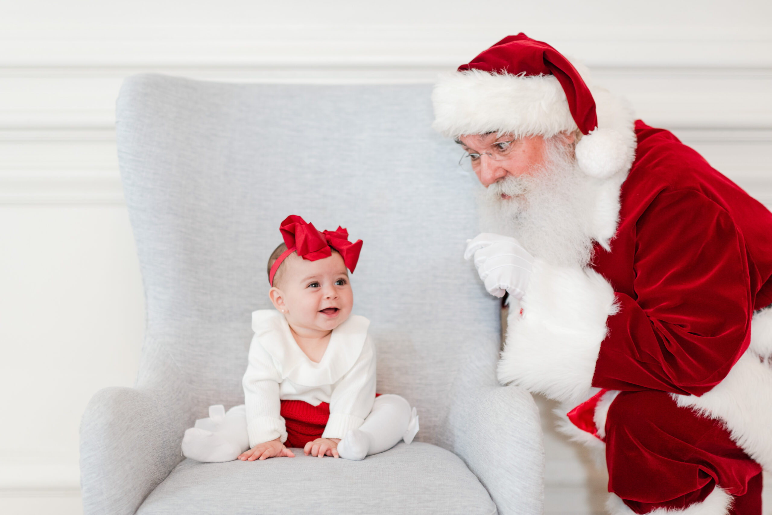3 month old baby girl sitting on a light blue elegant chair with Santa by Miami Lifestyle Photographers MSP Photography