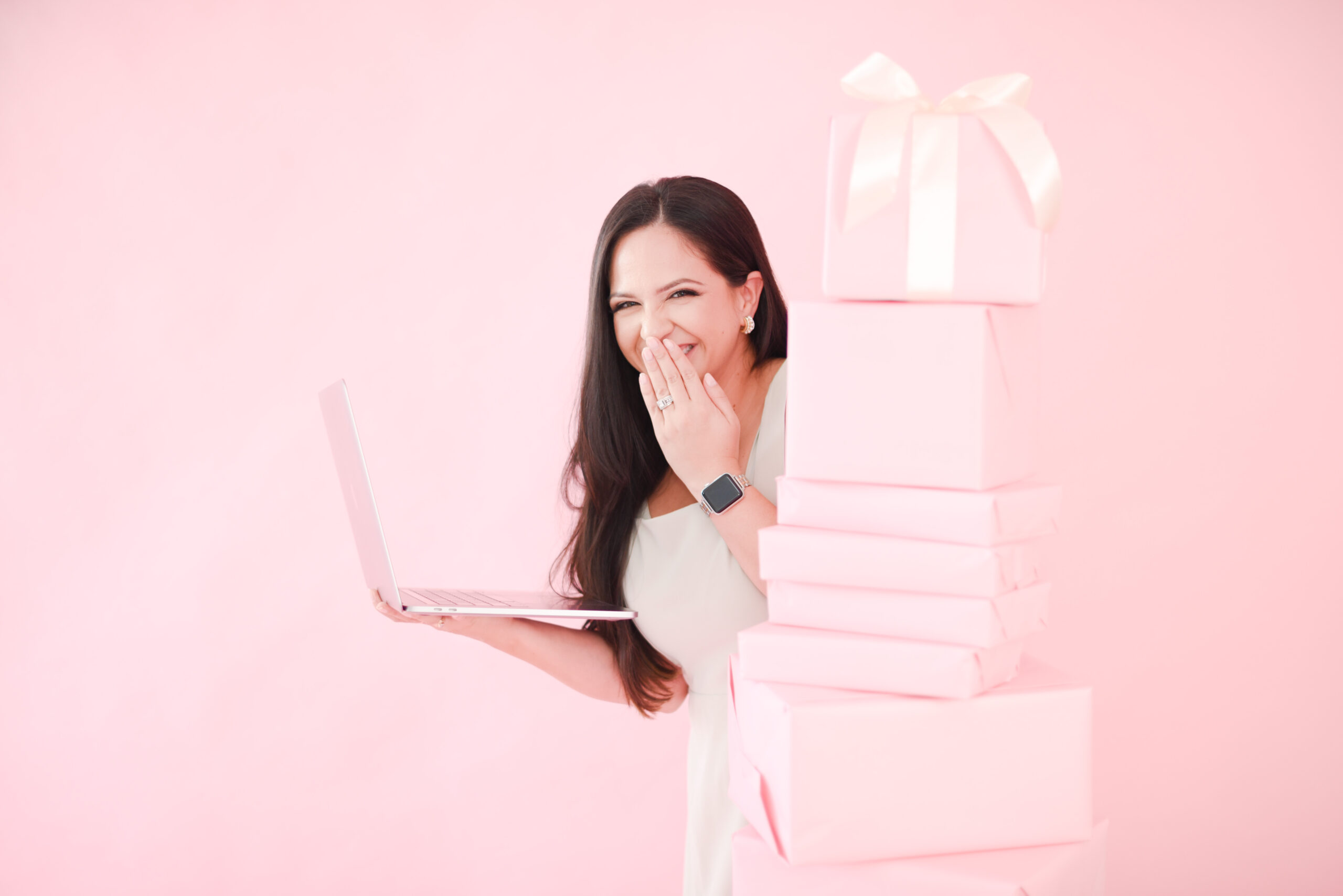 Photographer with laptop in a pink christmas mini session setup