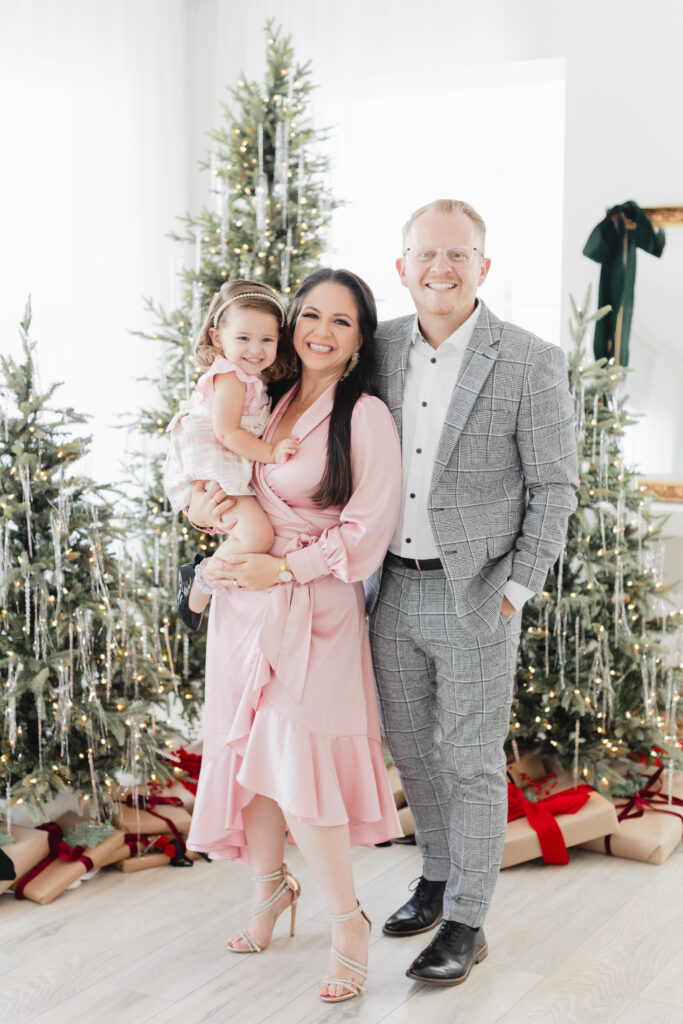 family of three in front of a christmas tree elegant outfits Miami Christmas Mini Session