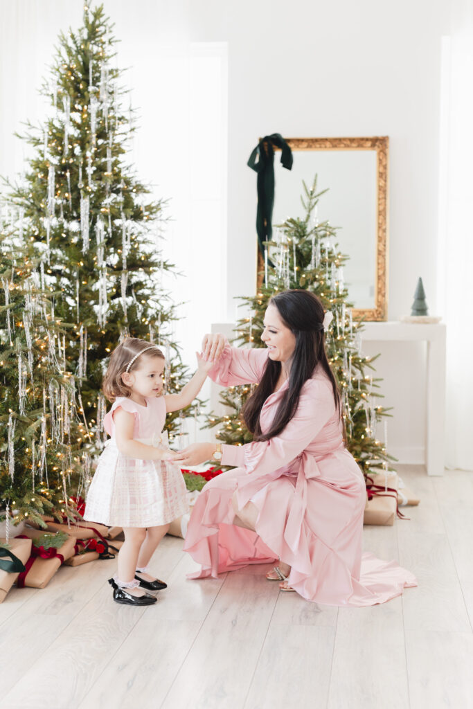 mother twirling daughter in front of a christmas tree elegant outfits Miami Christmas Mini Session