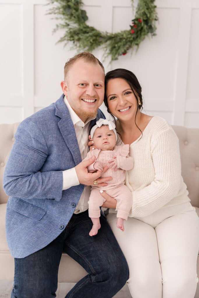 family of three mom and dad holding 2 month old baby Christmas mini sessions