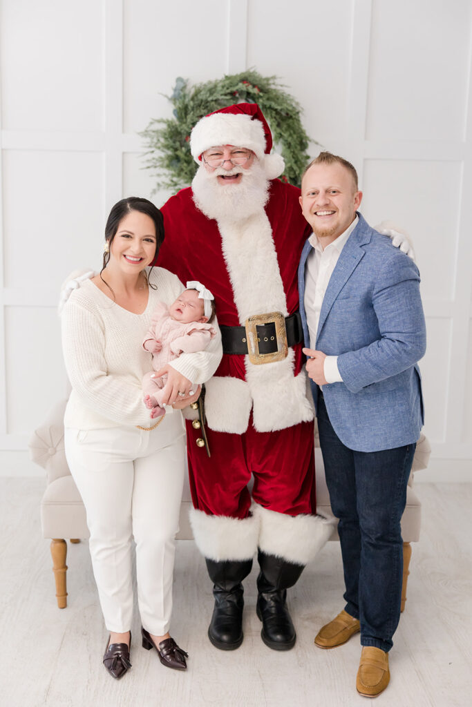 family of three mom and dad holding 2 month old baby Christmas mini sessions with Santa