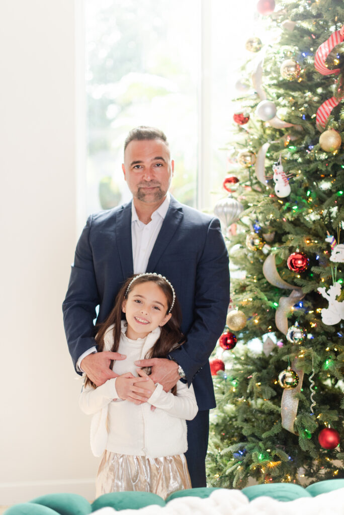 Father and daughter portrait in front of a Christmas tree wearing elegant Christmas outfits at in home Christmas Family Photoshoot